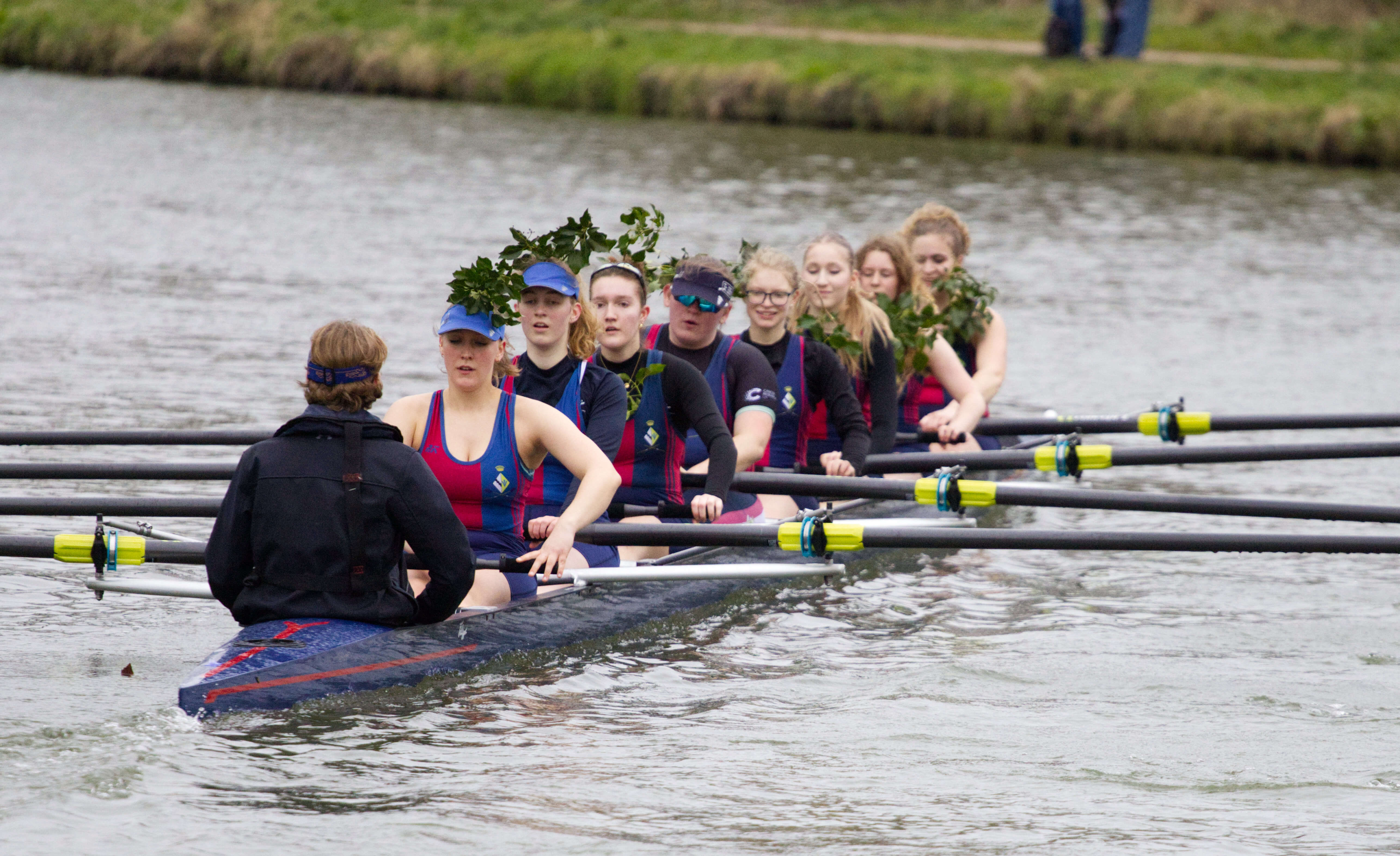 Crews rowing past willow trees on the river